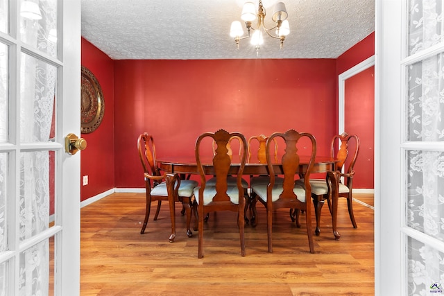 dining space with a notable chandelier, a textured ceiling, and wood finished floors