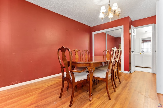 dining room with a chandelier, a textured ceiling, wood finished floors, and baseboards