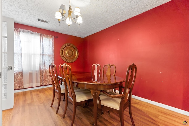 dining space featuring a chandelier, wood finished floors, visible vents, and baseboards