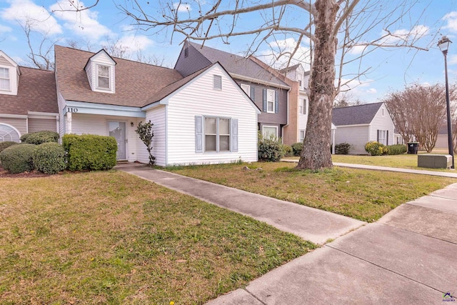 view of front of house featuring a shingled roof and a front yard