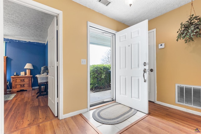 entryway featuring a textured ceiling, visible vents, and wood finished floors