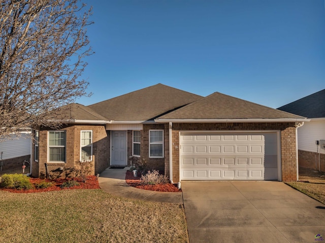 ranch-style home featuring brick siding, a shingled roof, concrete driveway, an attached garage, and a front yard