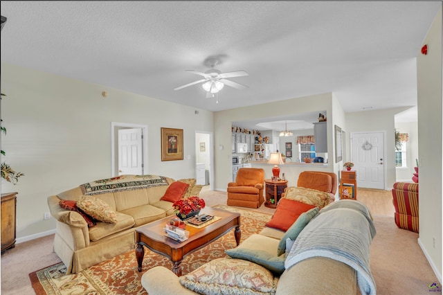 living room with ceiling fan, a textured ceiling, and baseboards