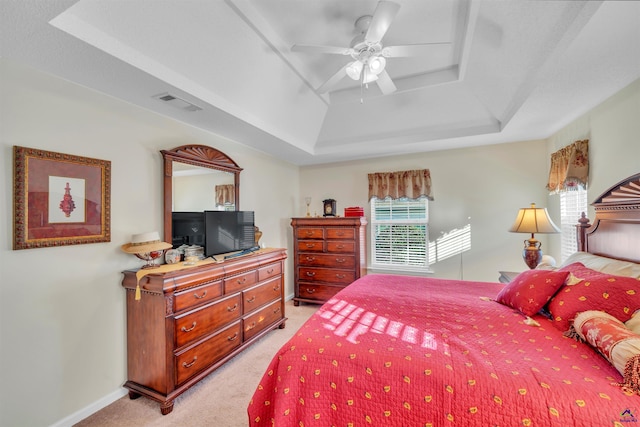 bedroom with light carpet, a ceiling fan, visible vents, baseboards, and a raised ceiling