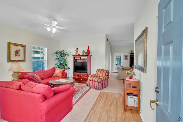 living area featuring a ceiling fan, baseboards, and light wood finished floors