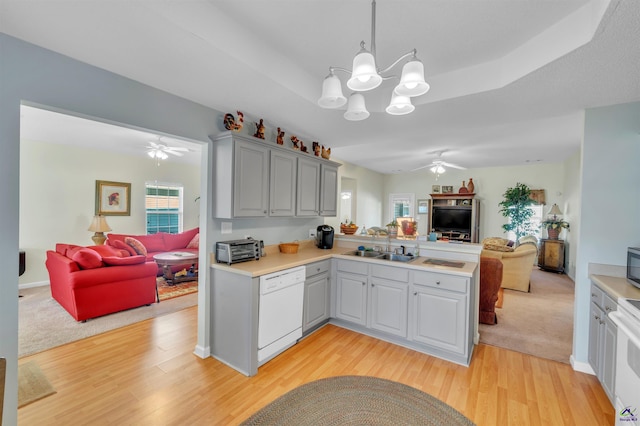 kitchen featuring a tray ceiling, open floor plan, white dishwasher, and a peninsula