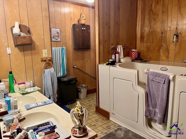 bathroom featuring washer / dryer, wood walls, a sink, and tile patterned floors