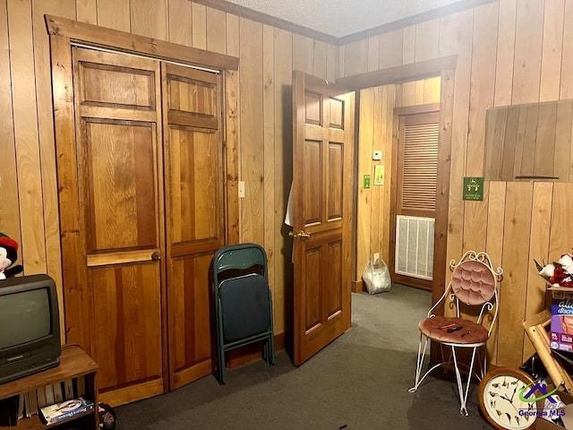 sitting room featuring carpet floors, wood walls, and visible vents