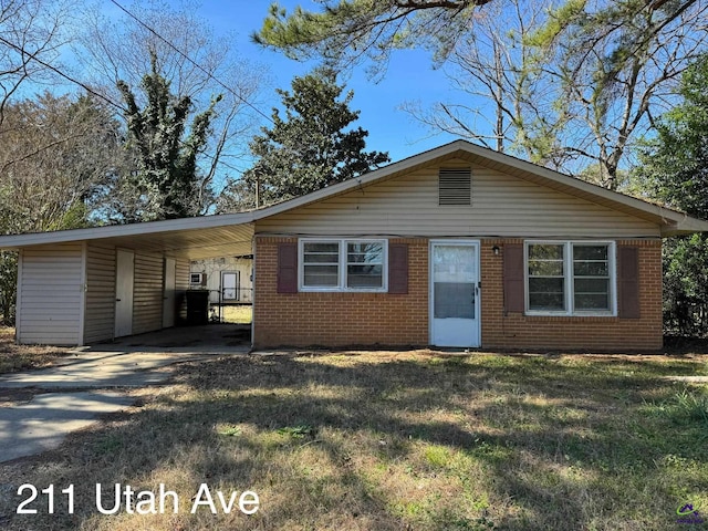 view of front of house featuring an attached carport, brick siding, driveway, and a front lawn