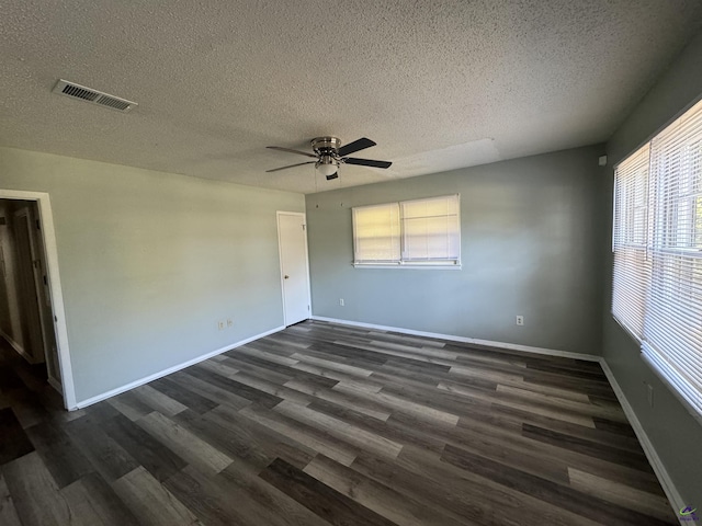 unfurnished room featuring baseboards, a textured ceiling, visible vents, and dark wood-style flooring