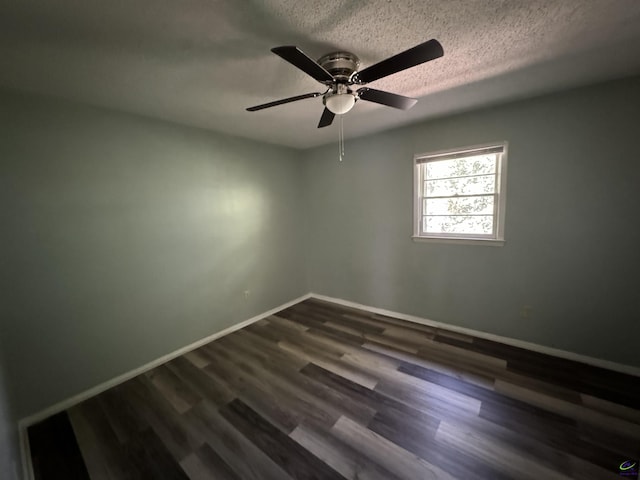 empty room featuring dark wood-style flooring, a textured ceiling, and baseboards