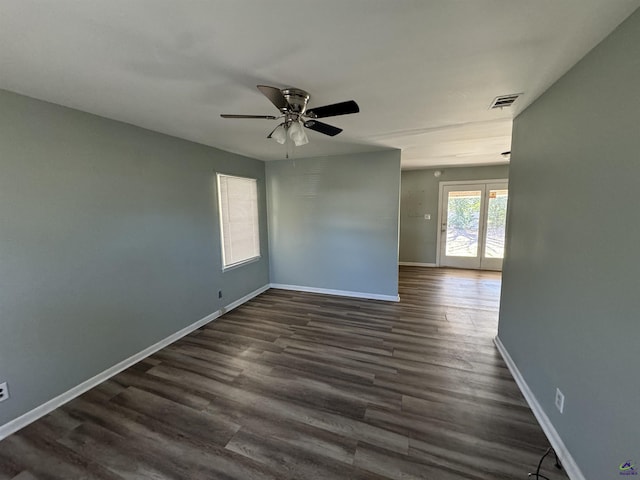 spare room with dark wood-type flooring, ceiling fan, and baseboards