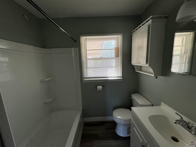 bathroom featuring baseboards, toilet, wood finished floors, tub / shower combination, and vanity