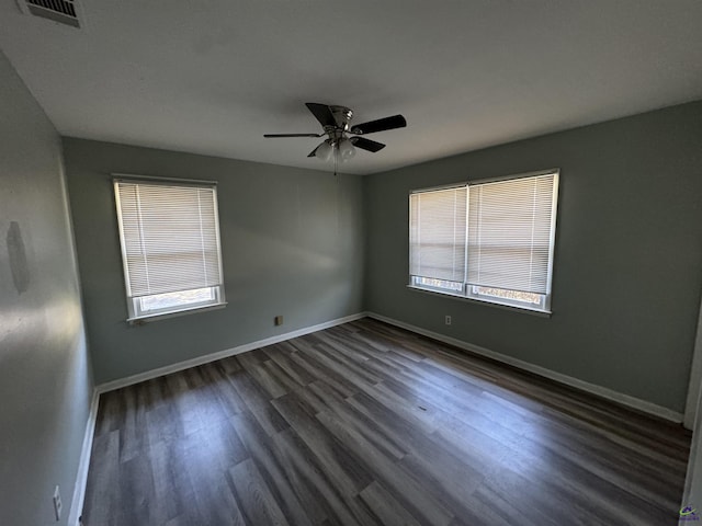 spare room featuring a ceiling fan, visible vents, baseboards, and wood finished floors