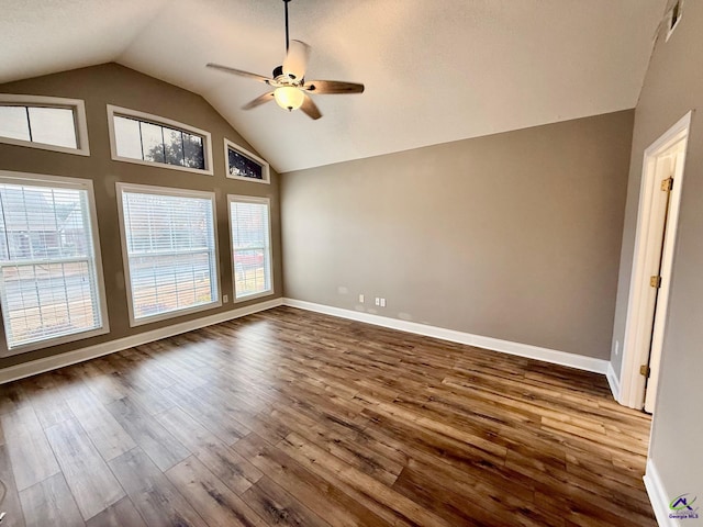 spare room with vaulted ceiling, dark wood-style flooring, a ceiling fan, and a healthy amount of sunlight