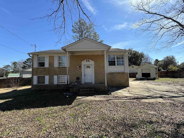 view of front of home with fence, an outbuilding, and brick siding