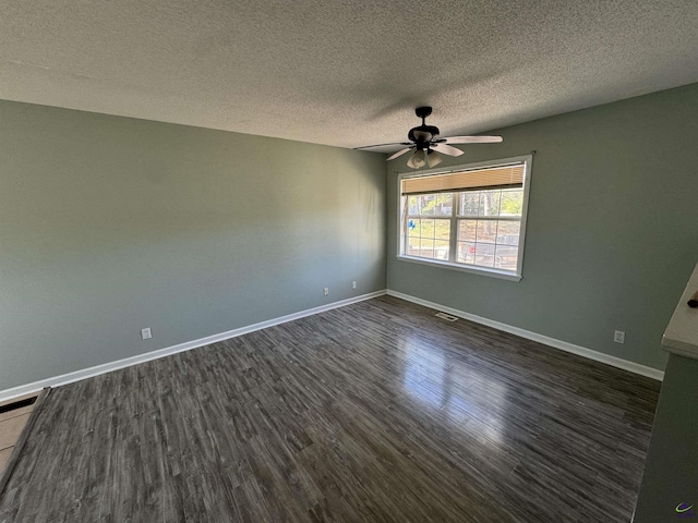 empty room featuring ceiling fan, dark wood-type flooring, a textured ceiling, and baseboards