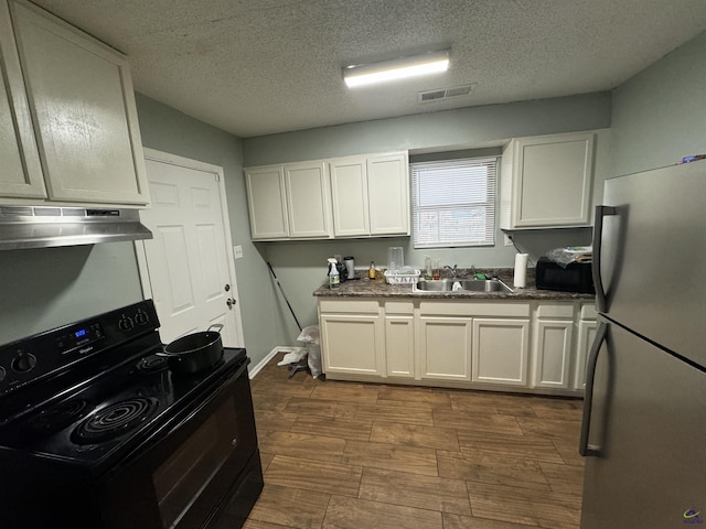 kitchen with white cabinetry, a sink, under cabinet range hood, and black appliances