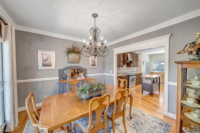 dining space with ornamental molding, a notable chandelier, light wood-style flooring, and baseboards