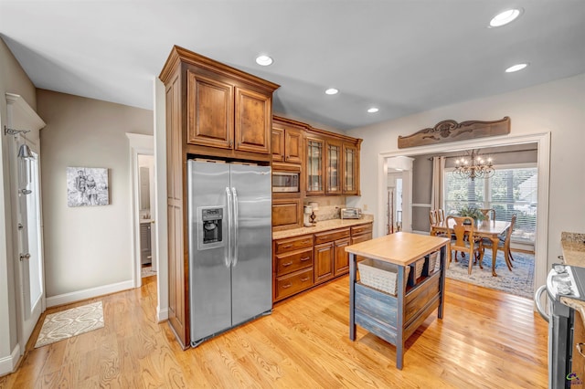 kitchen featuring light wood-style flooring, glass insert cabinets, brown cabinets, stainless steel appliances, and recessed lighting