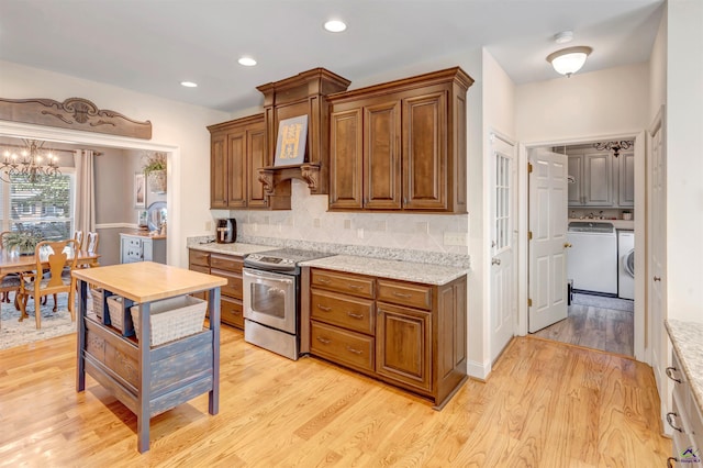 kitchen featuring tasteful backsplash, electric range, light wood-style flooring, and washing machine and dryer