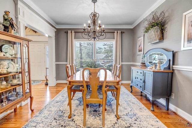 dining space with an inviting chandelier, light wood-style flooring, ornamental molding, and baseboards