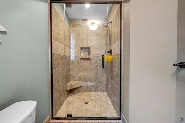 bathroom featuring toilet and a shower stall