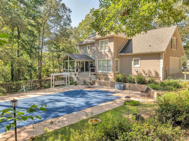 rear view of property featuring a sunroom, a patio area, fence, and stucco siding