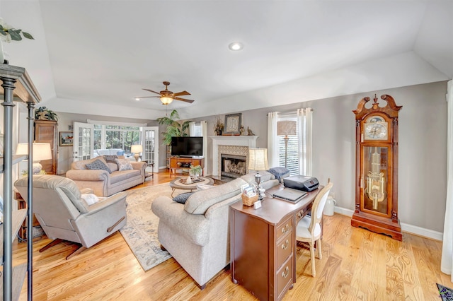 living area with a ceiling fan, a healthy amount of sunlight, a fireplace, and light wood finished floors