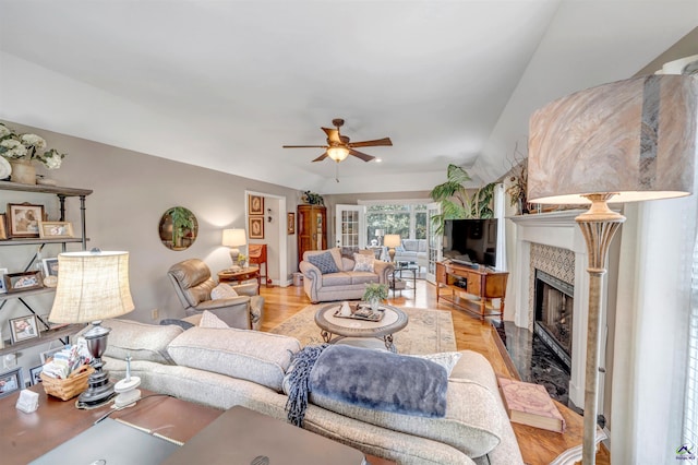 living room featuring a ceiling fan, a fireplace, and light wood-style flooring