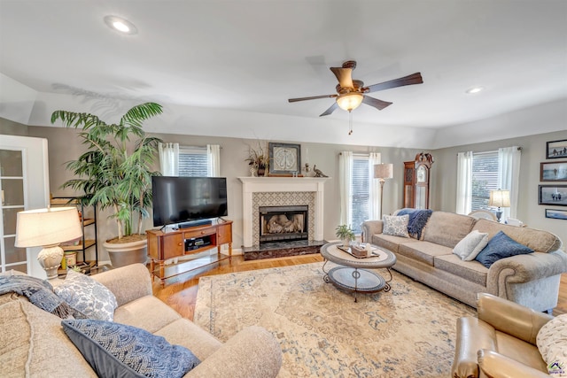 living area with ceiling fan, a tiled fireplace, wood finished floors, and recessed lighting