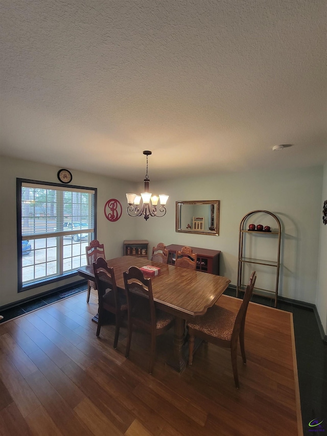 dining space with a notable chandelier, a textured ceiling, and wood finished floors