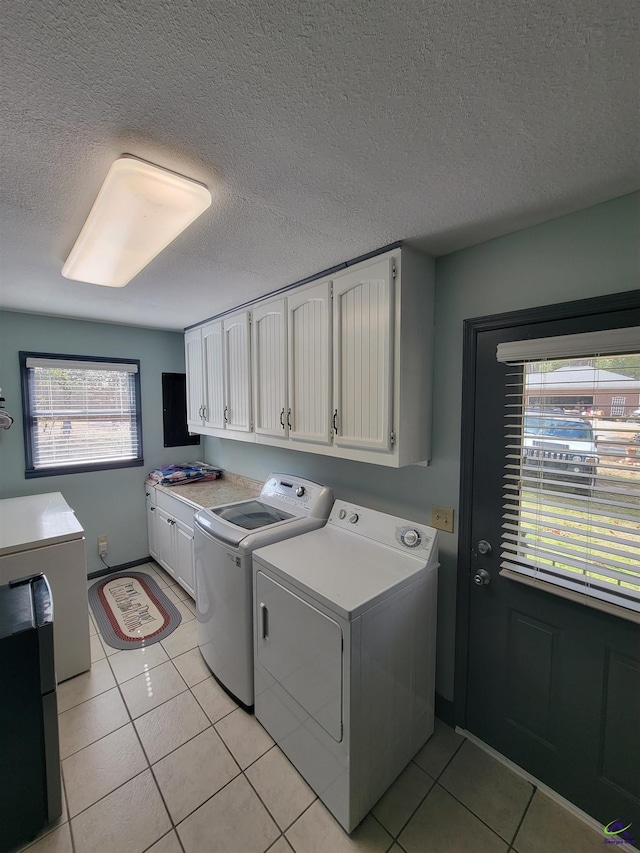 washroom with light tile patterned floors, a textured ceiling, cabinet space, and washer and dryer