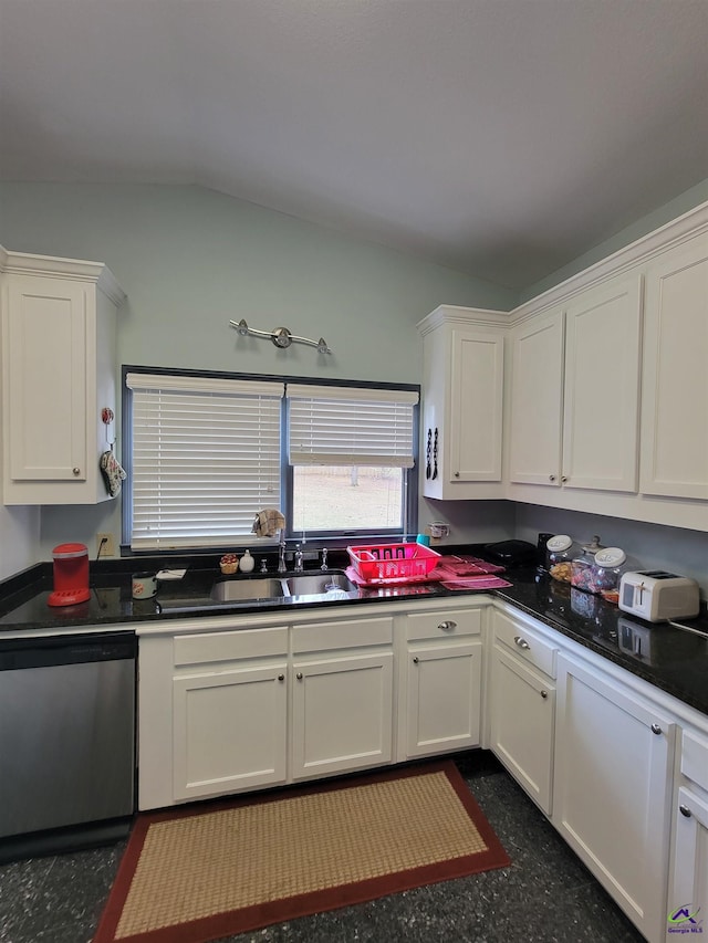 kitchen with stainless steel dishwasher, dark countertops, a sink, and white cabinetry