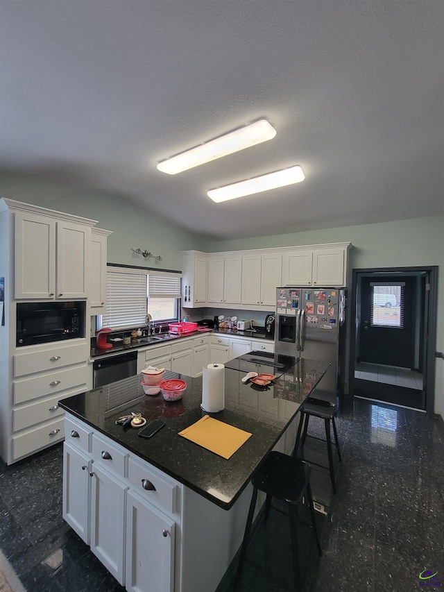 kitchen with a kitchen bar, a spacious island, white cabinetry, and black appliances