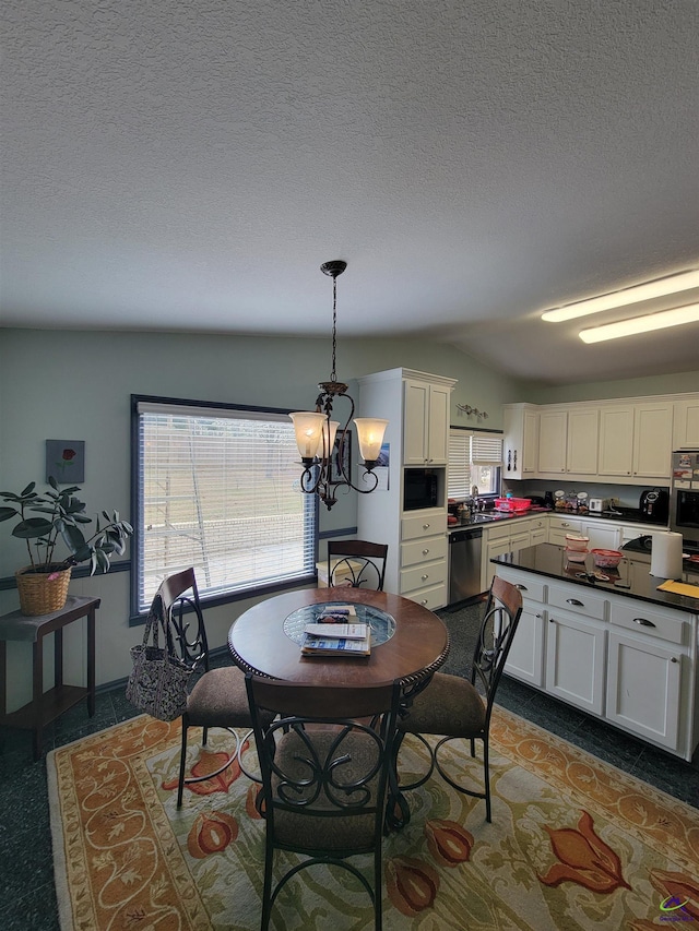 dining room with a notable chandelier, dark tile patterned flooring, a textured ceiling, and a healthy amount of sunlight