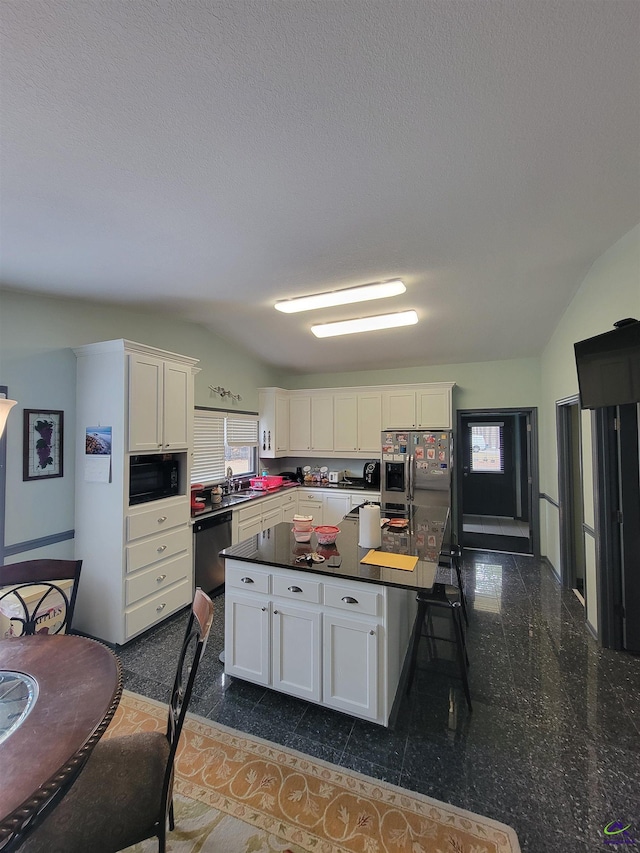 kitchen with stainless steel appliances, dark countertops, granite finish floor, white cabinets, and a sink