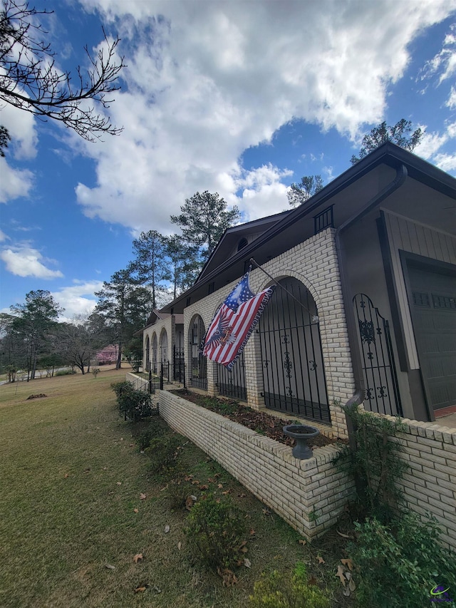 view of property exterior featuring a garage, brick siding, and a lawn