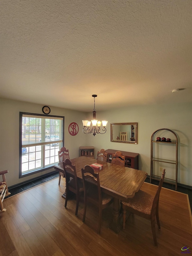 dining room with a chandelier, a textured ceiling, and wood finished floors