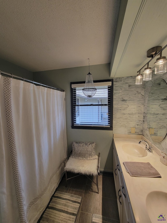 bathroom with double vanity, a textured ceiling, and a sink
