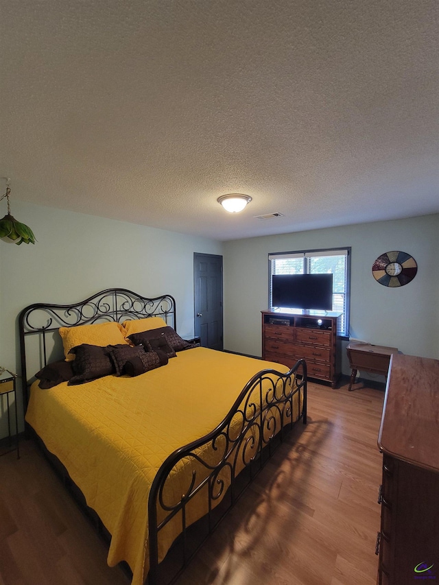 bedroom featuring a textured ceiling and wood finished floors