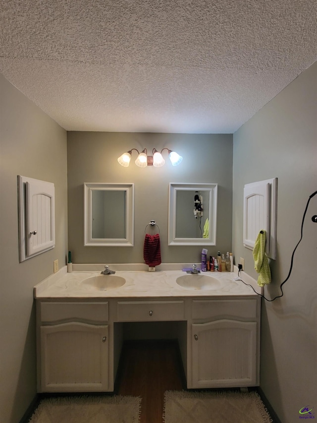 bathroom featuring double vanity, a textured ceiling, and a sink