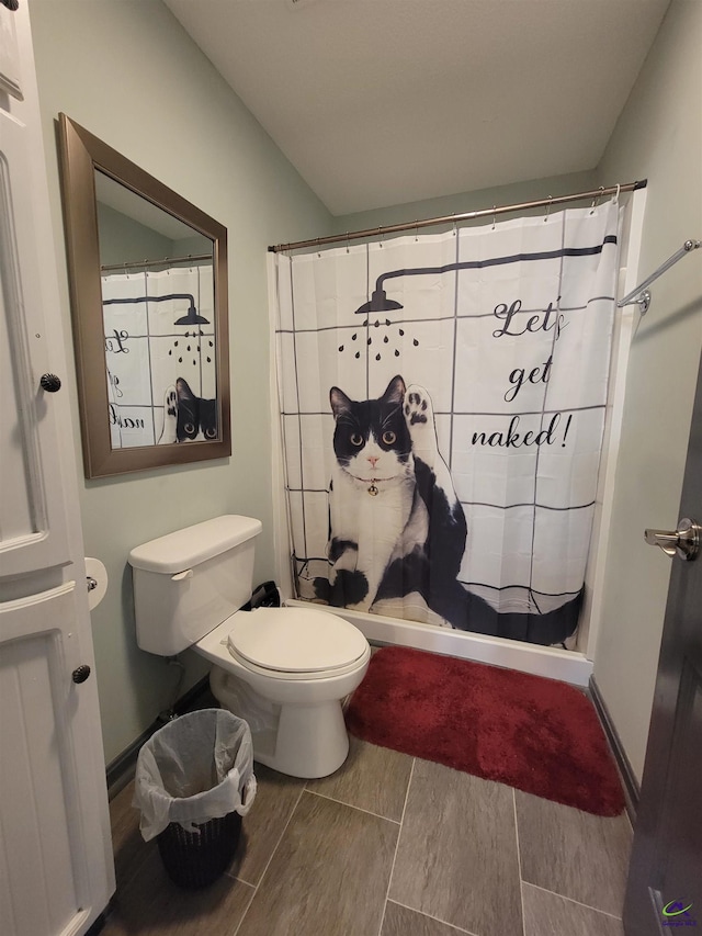 bathroom with lofted ceiling, toilet, and a shower with curtain