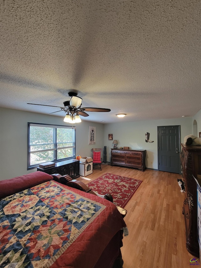 bedroom featuring light wood-style floors, ceiling fan, and a textured ceiling