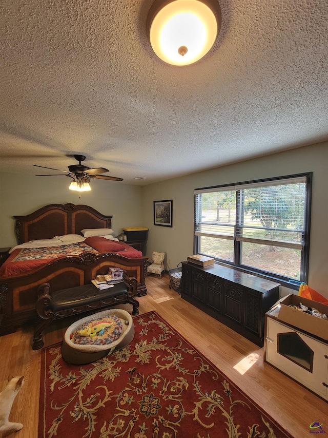 bedroom featuring a textured ceiling, light wood finished floors, multiple windows, and a ceiling fan