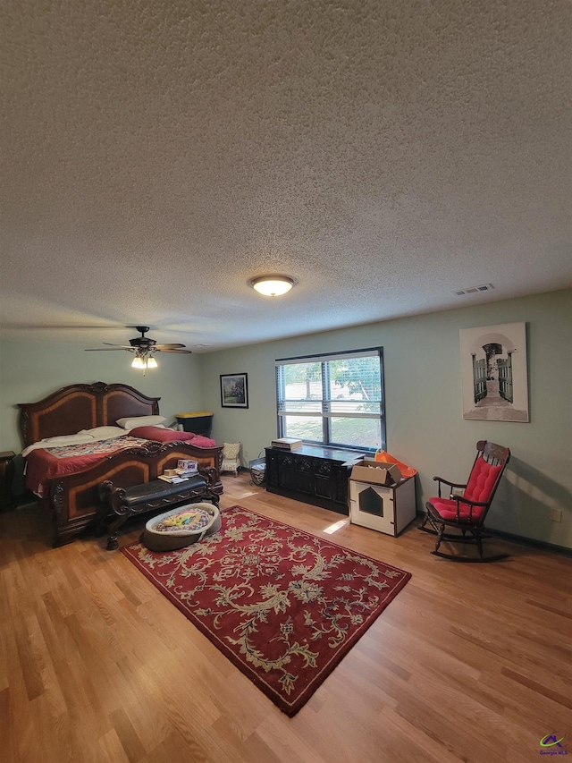 bedroom with a textured ceiling, wood finished floors, and visible vents