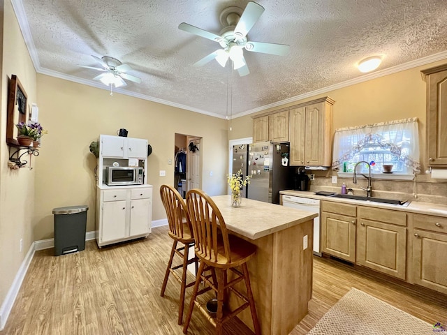 kitchen with light wood finished floors, light countertops, appliances with stainless steel finishes, light brown cabinets, and a sink