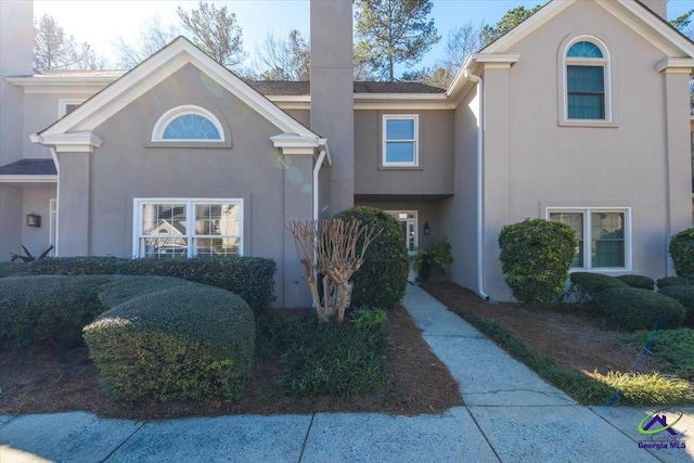 view of front facade with a chimney and stucco siding