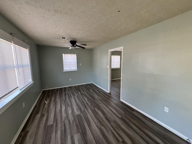 spare room with visible vents, dark wood-type flooring, a ceiling fan, a textured ceiling, and baseboards