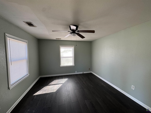 spare room featuring ceiling fan, a textured ceiling, visible vents, baseboards, and dark wood-style floors